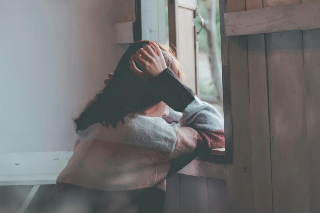 Photo of a Person Leaning on Wooden Window